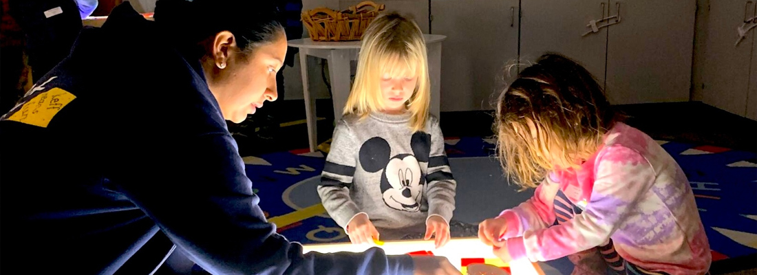 kids building with magna tiles on a light box