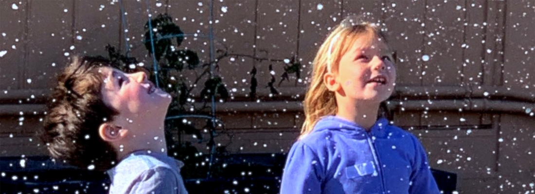 two kids playing in snow on a field